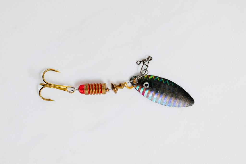 A close-up shot of a colorful metallic fishing lure with hook on a white surface.